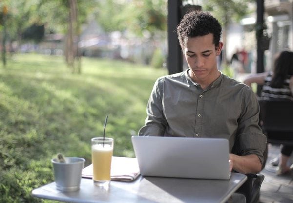 Focused black male freelancer using laptop in street cafe
